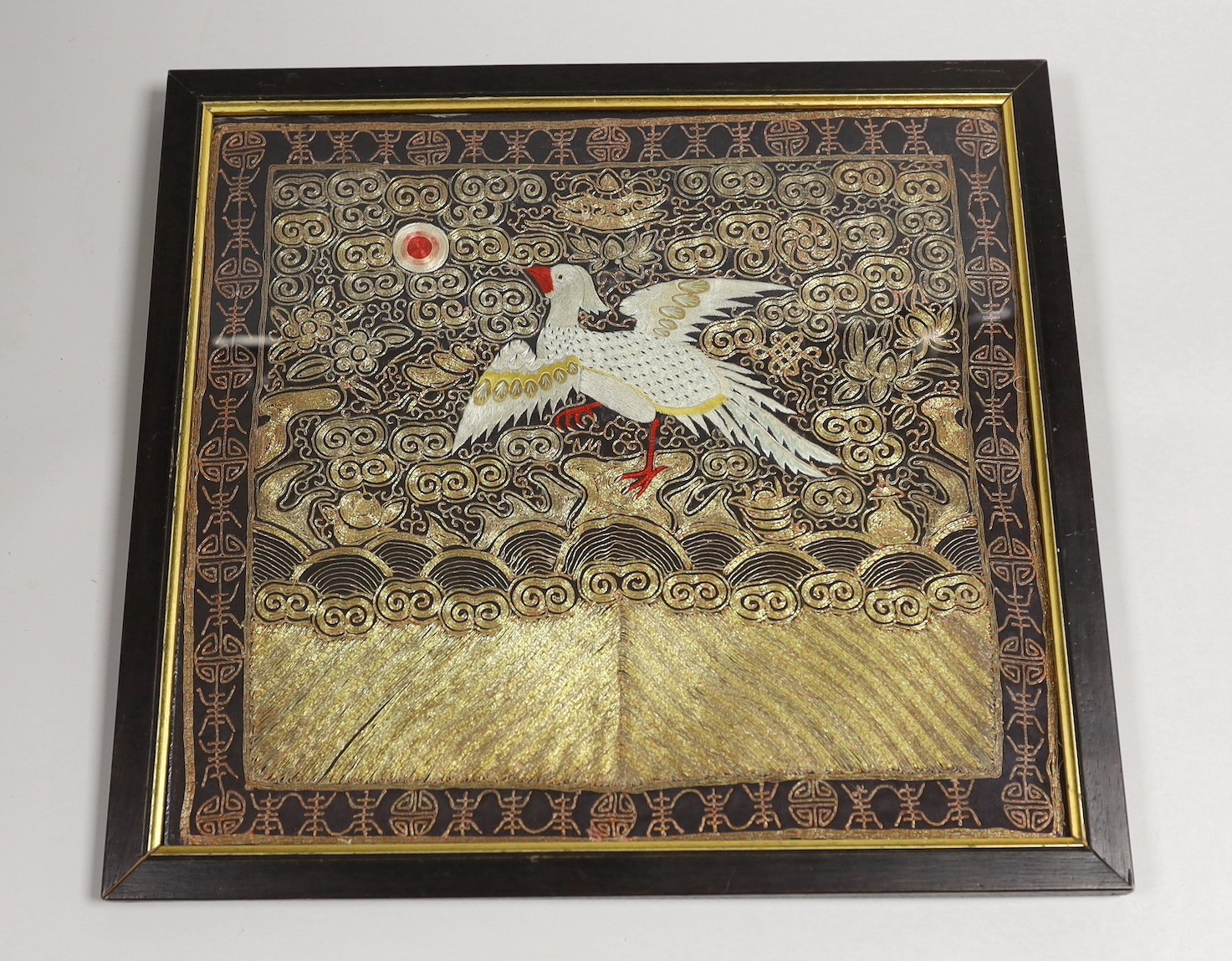 A Chinese silk ornately coloured and gold thread embroidered rank badge, of a Phoenix, 32cms wide x 29cms high